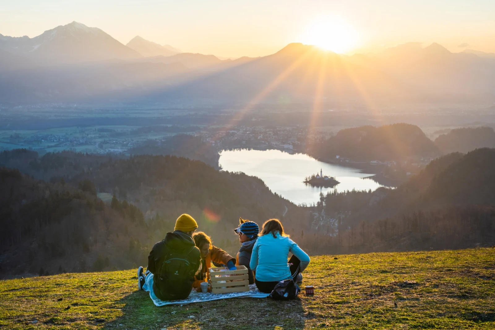 Group of friends having breakfast on a mountain meadow at sunrise