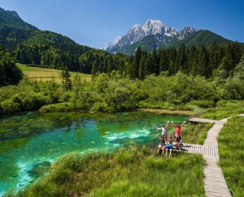 Happy Group of Friends are raising Hands Up at Zelenci Lake, Slovenia