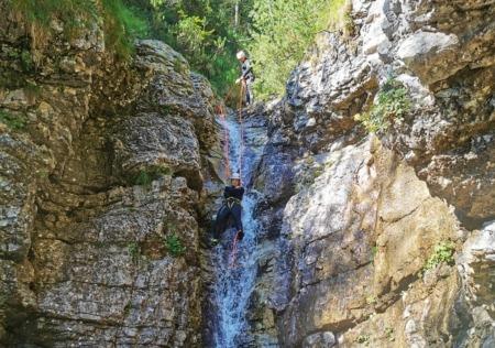 An adventurer enjoying natural tobogganing, leaping into the water, and rappelling down a waterslide in Triglav National Park's canyons