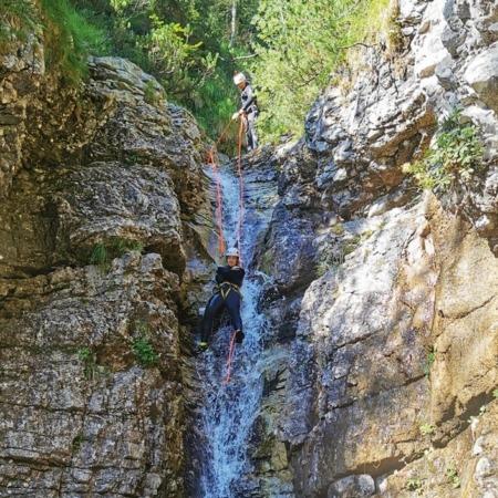 An adventurer enjoying natural tobogganing, leaping into the water, and rappelling down a waterslide in Triglav National Park's canyons
